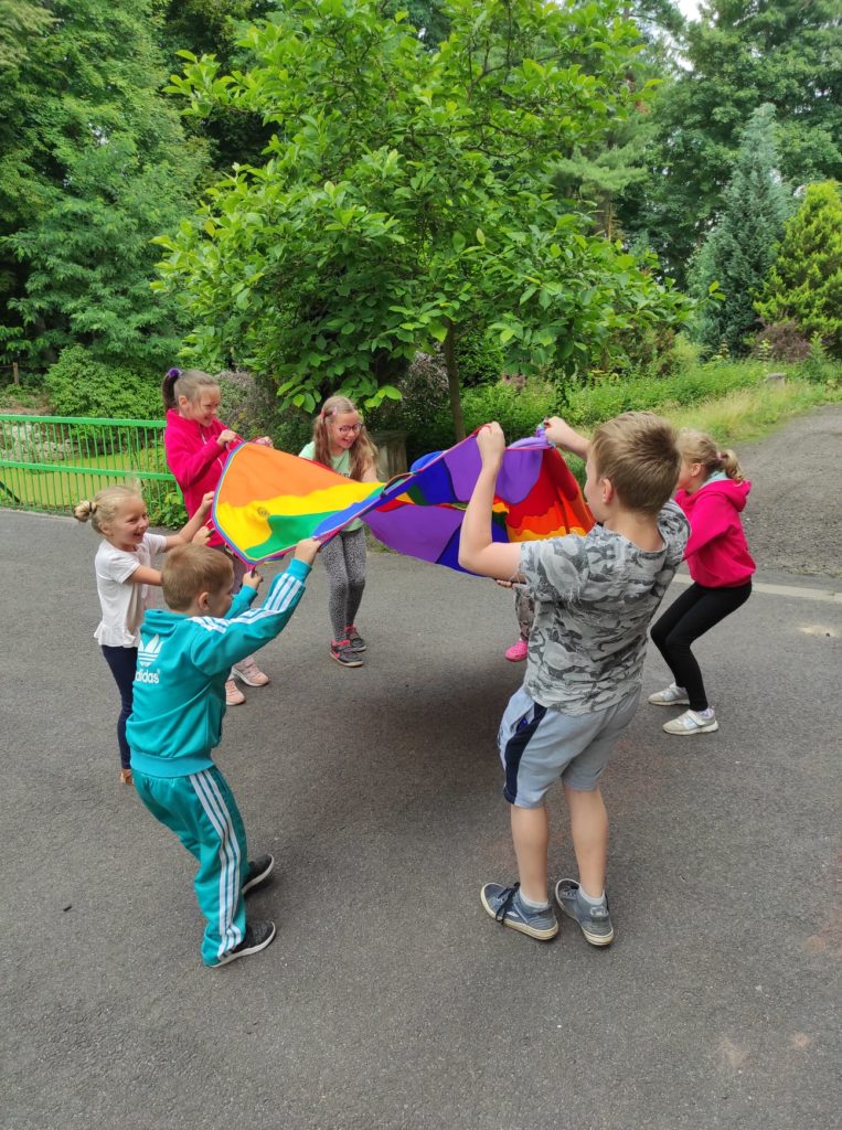 Grupa dzieci bawi się kolorową chustą.