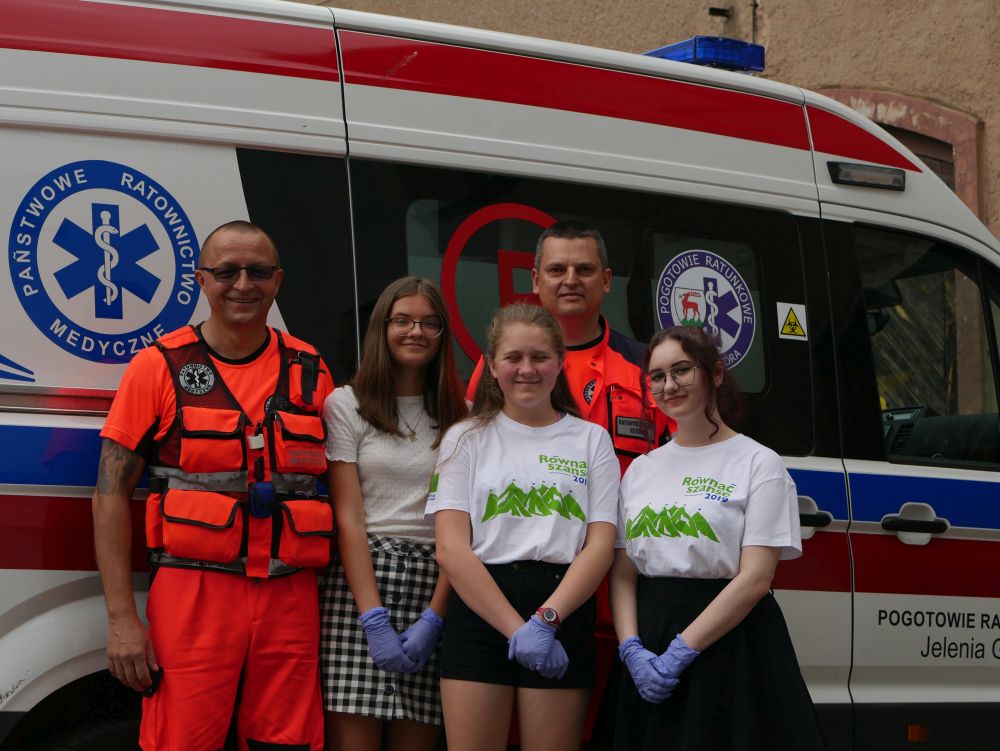 Dwóch stojących ratowników medycznych i trzy dziewczyny.