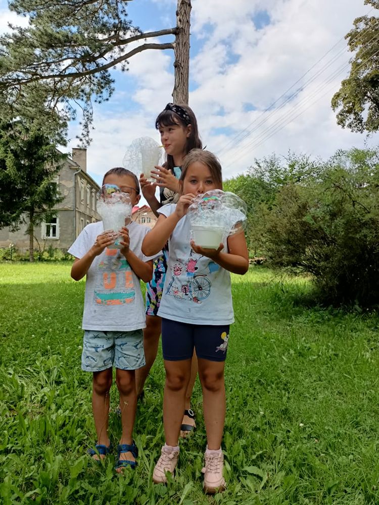 Trójka stojących dzieci robiących bańki mydlane