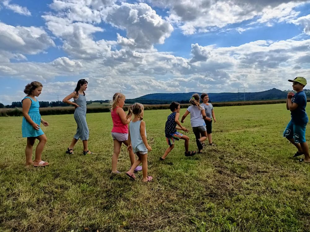 Grupa dzieci biegająca po trawie