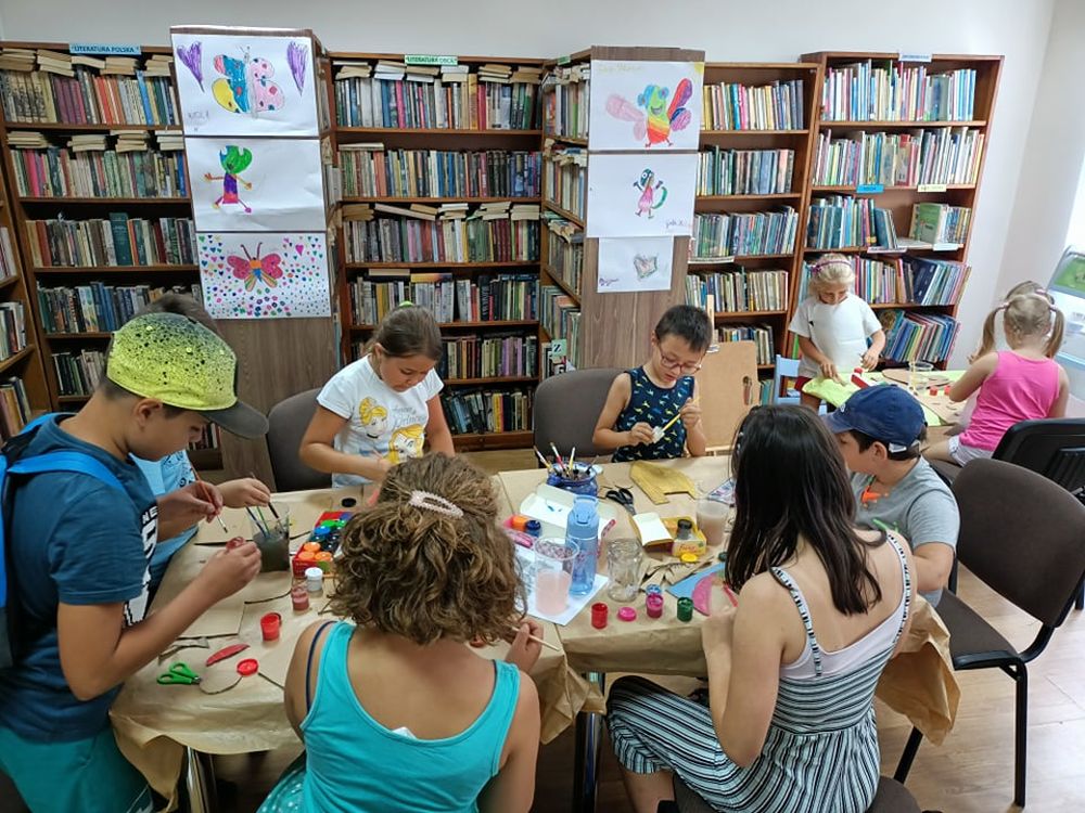 Siedzące przy stole dzieci malujące farbami
