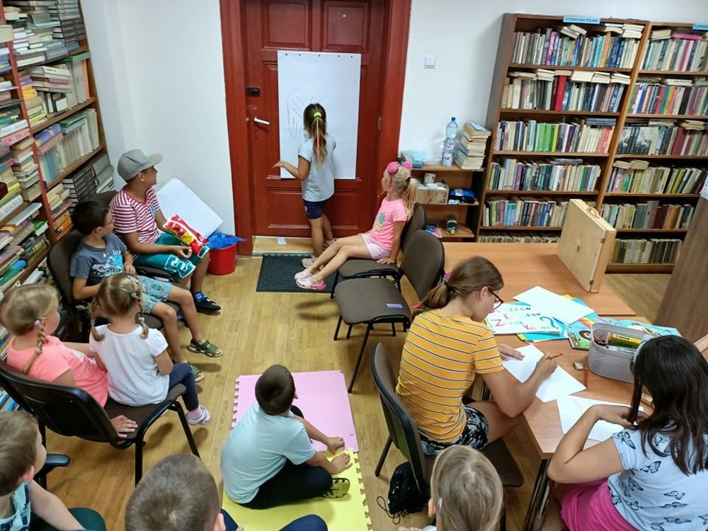 Grupa dzieci siedzących w bibliotece