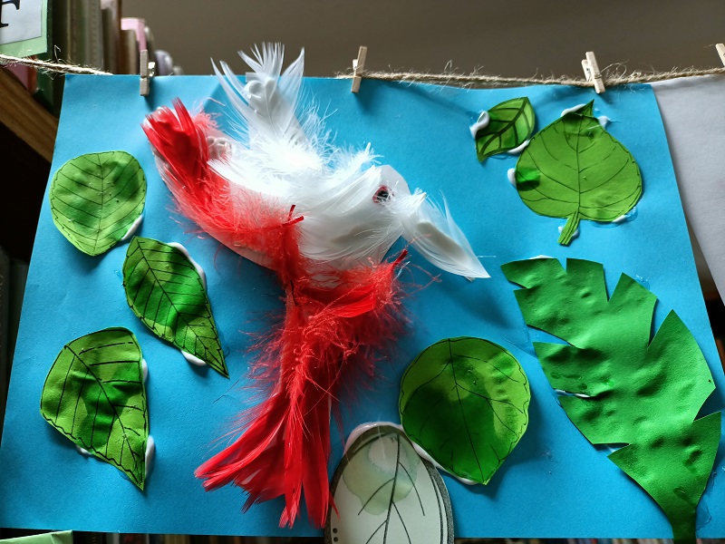 Praca plastyczna z ptakiem, ozdobionym piórkami.