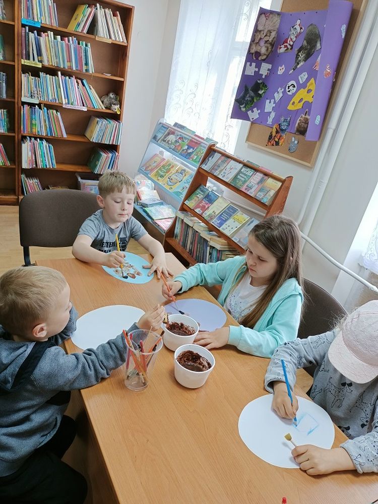 Dzieci siedzące przy stole i malujące obrazki.
