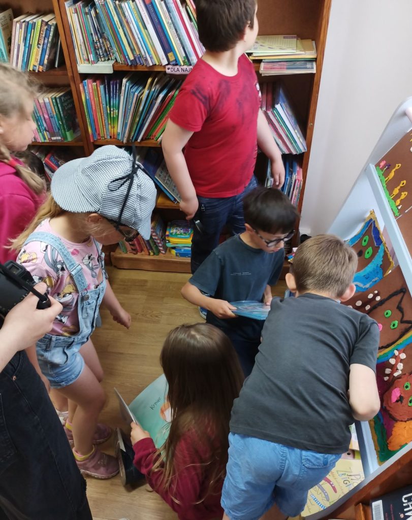 Grupa dzieci przy regale z książkami