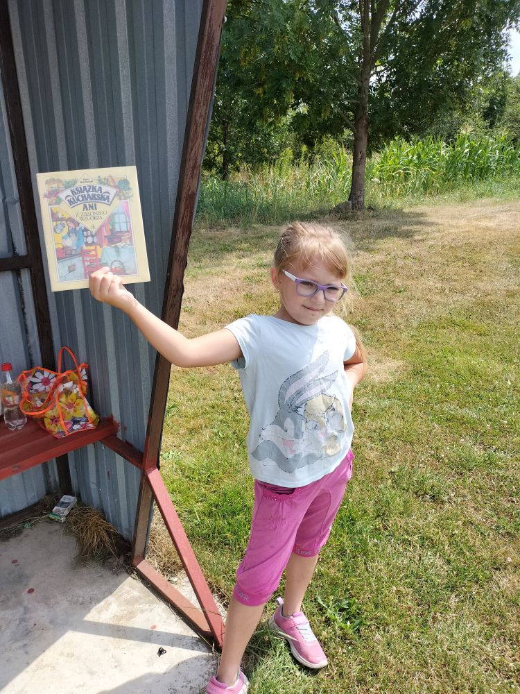 dziewczynka prezentuje książkę trzymając w prawej ręce