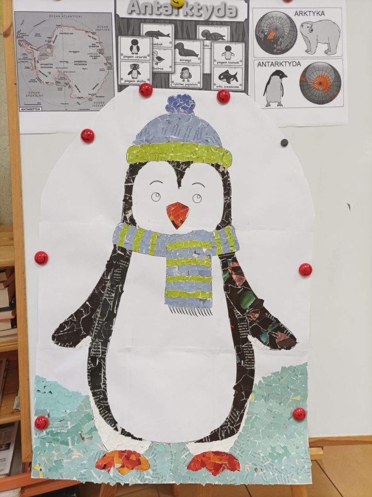 Na pierwszym planie widać dużego pingwina, wykonanego z wydzieranych kolorowych gazet. Nad nim jest mapa Antarktydy, napis Antarktyda, czarno-białe obrazki zwierząt żyjących na niej. Po prawej stronie, nad dużym pingwinem, czarno-biały obrazek z Arktyką i białym niedźwiedziem oraz Antarktydą i pingwinem.